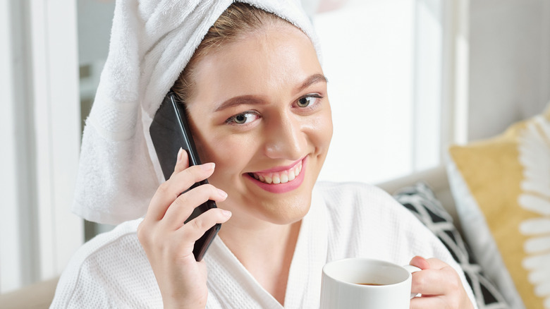 Woman drinking coffee and talking on the phone after cold shower