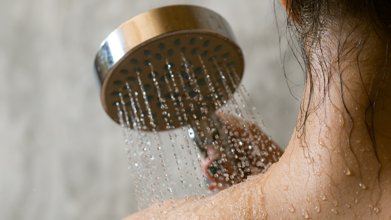 Woman running water across shoulder in cold shower