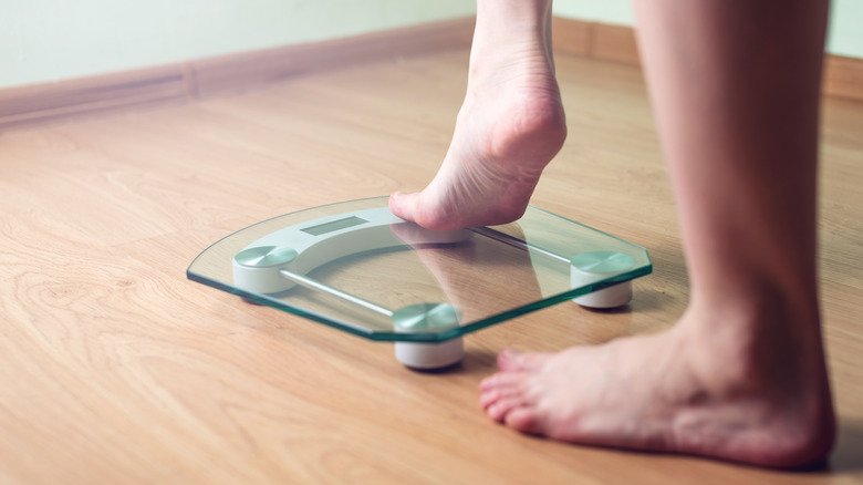 Woman stepping on scale after taking cold shower