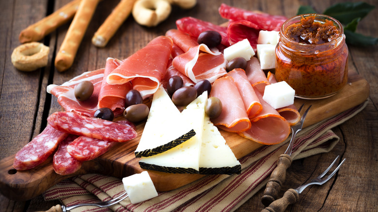 meats and cheeses served alongside olives on a charcuterie board