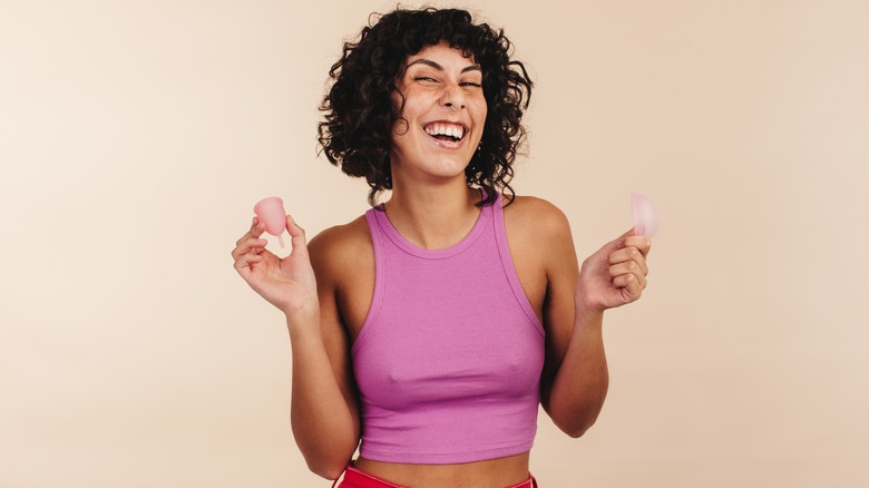 Woman holding menstrual cup and disc