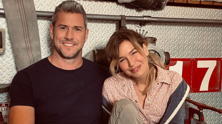 Ant Anstead and Renee Zellweger smiling and sitting on the back of a fire engine