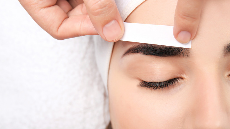 woman strip waxing eyebrow