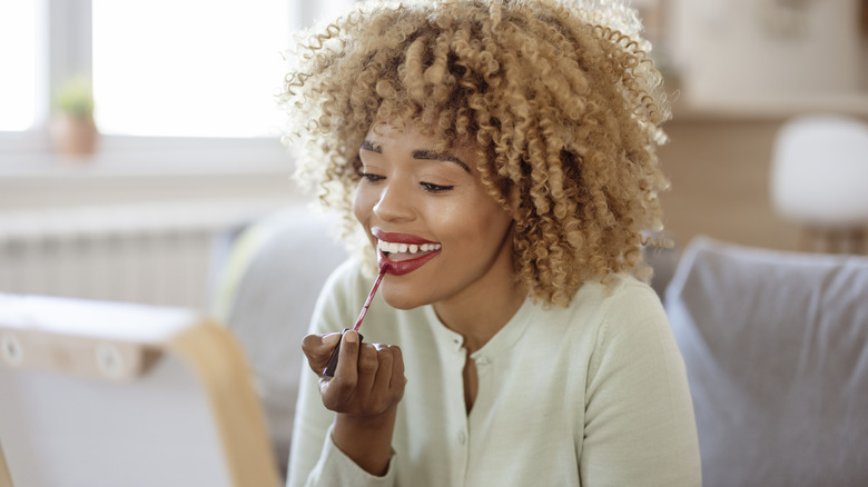 Woman smiling applying lip gloss