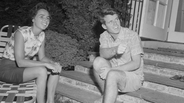 A young Ethel Kennedy and Robert F. Kennedy sitting on a set of stairs.