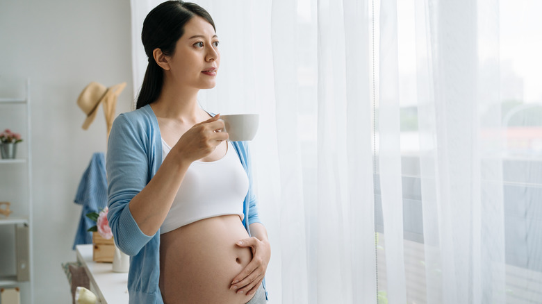 Pregnant woman holding cup of coffee