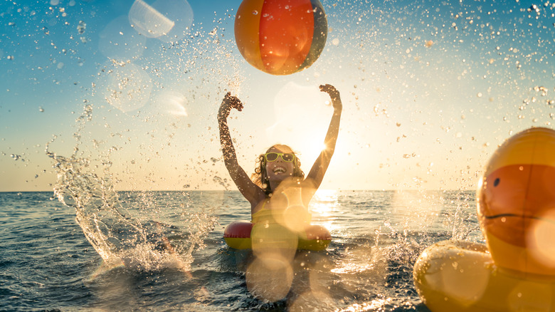 A smiling girl playing with a beach ball in the ocean 