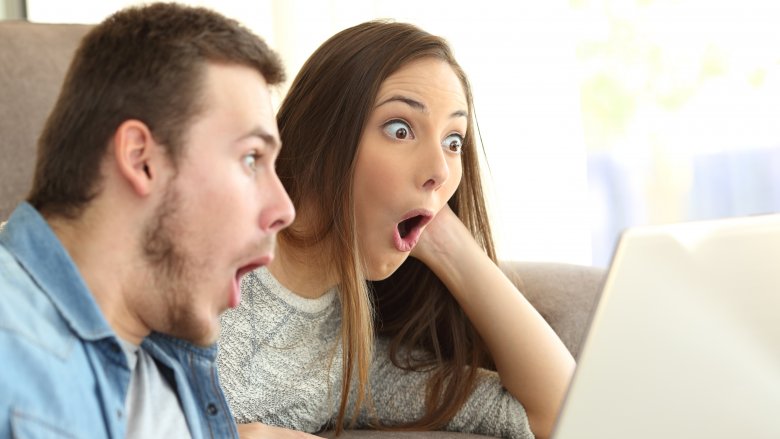 couple shocked looking at computer