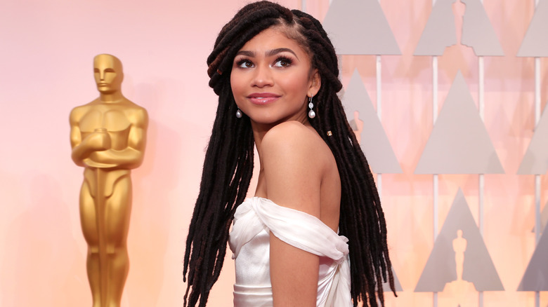 Zendaya posing in front of Oscars' statue