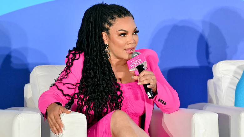 Egypt Sherrod sitting onstage and speaking into a microphone 