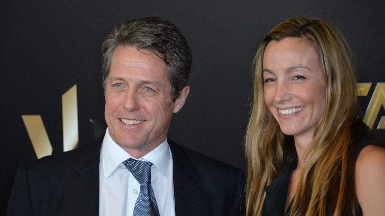 Hugh Grant posing with his wife, Anna Eberstein, at an event