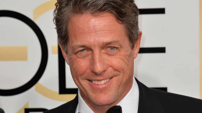 Hugh Grant smiling in a suit