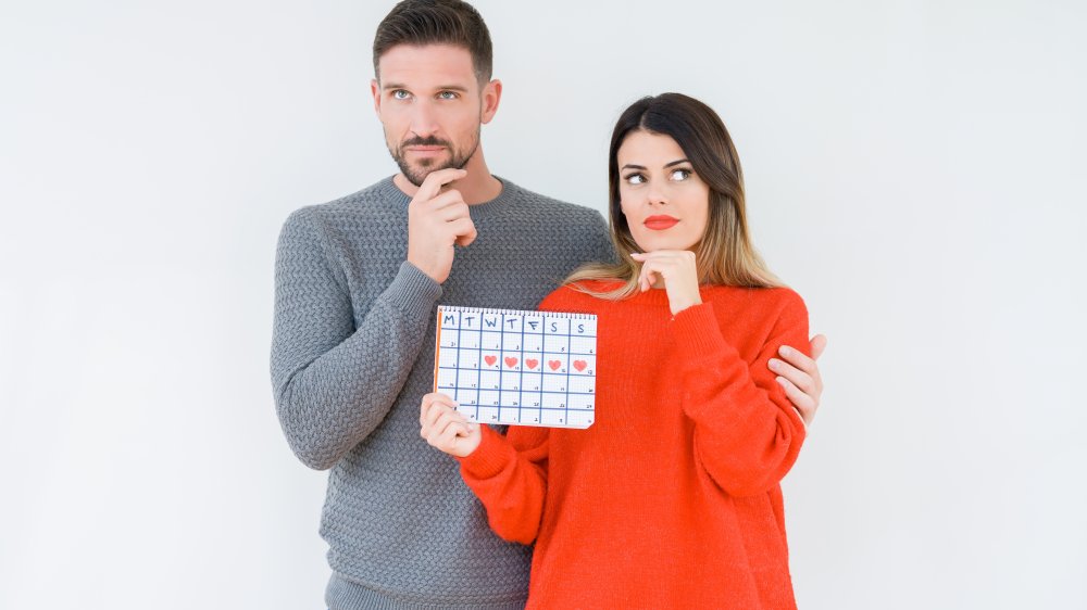 couple holding ovulation calendar