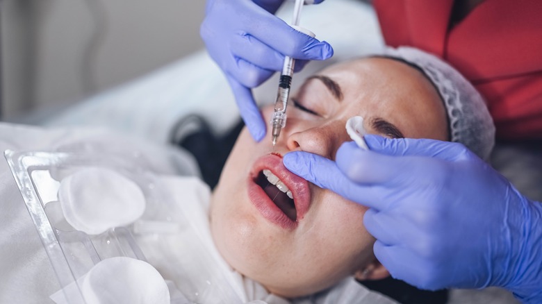 Woman receiving painful lip fillers