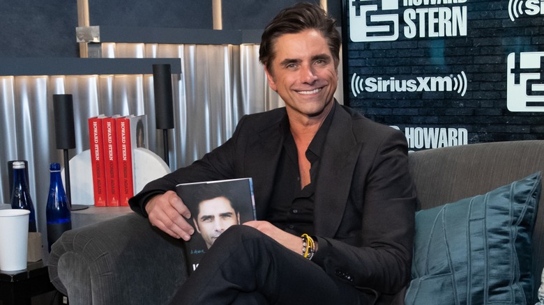 actor John Stamos holding his memoir