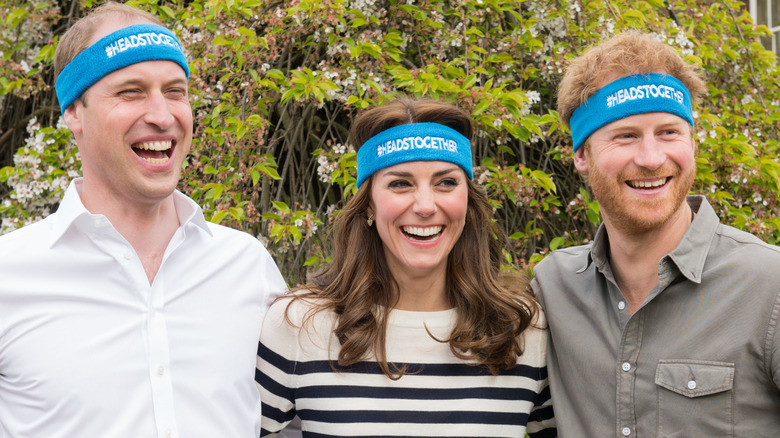 Princess Catherine and Prince Harry smiling with Prince William