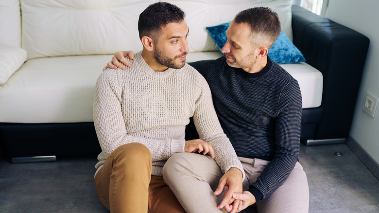 Two men talking, holding each other