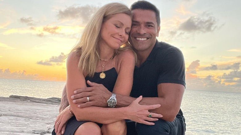  Kelly Ripa and Mark Consuelos embracing on beach