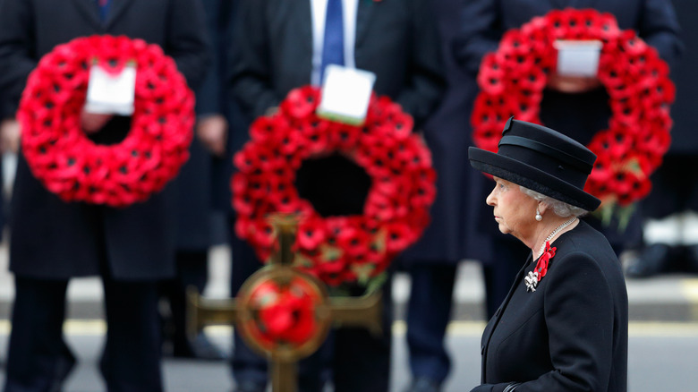 Queen Elizabeth II in front of poppy wreaths 