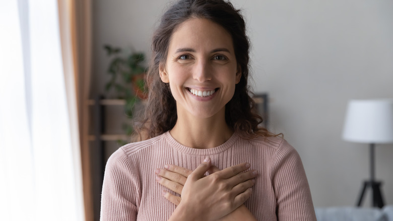 A woman places her hands over her chest. 