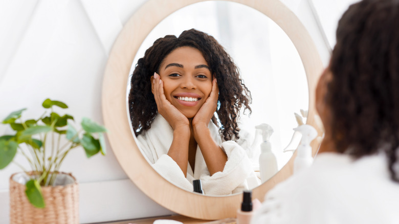 A woman smiles at herself in the mirror. 