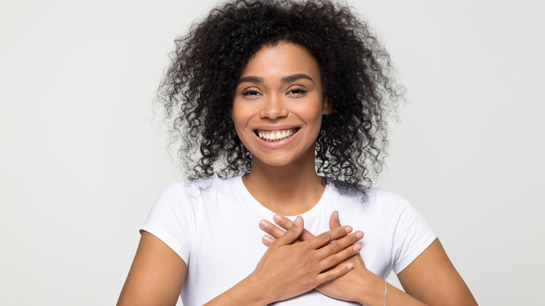 woman smiling and holding hands over her heart