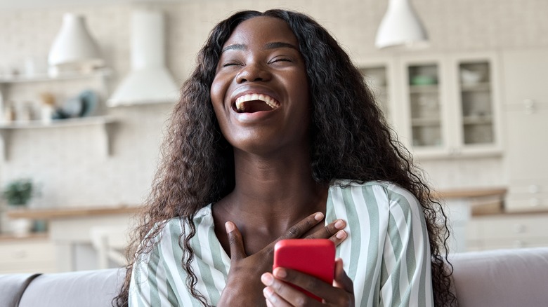 woman laughing while holding phone