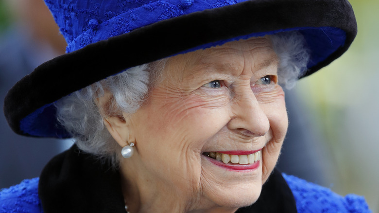 Queen Elizabeth smiling in a blue hat