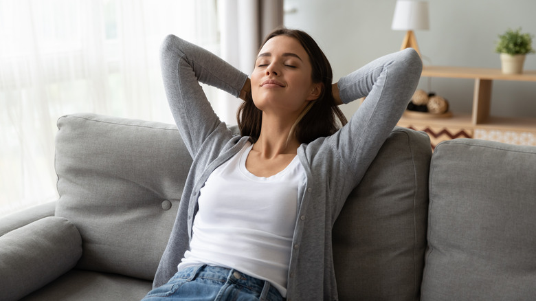 Young woman leaning back with her arms behind her head 