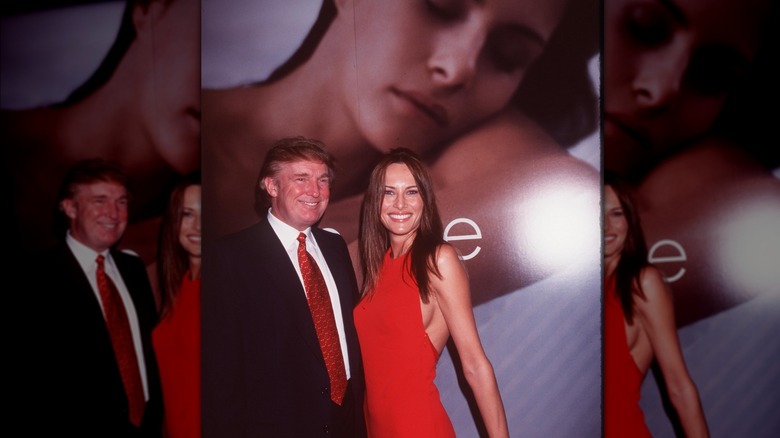 Donald Trump and Melania Trump pose in front of large photo of Trump