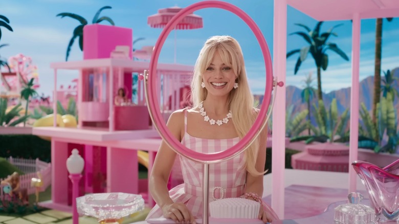 Margot Robbie as Barbie smiling into a mirror