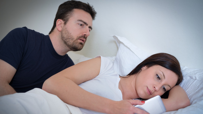 man looking over wife's shoulder while she's texting