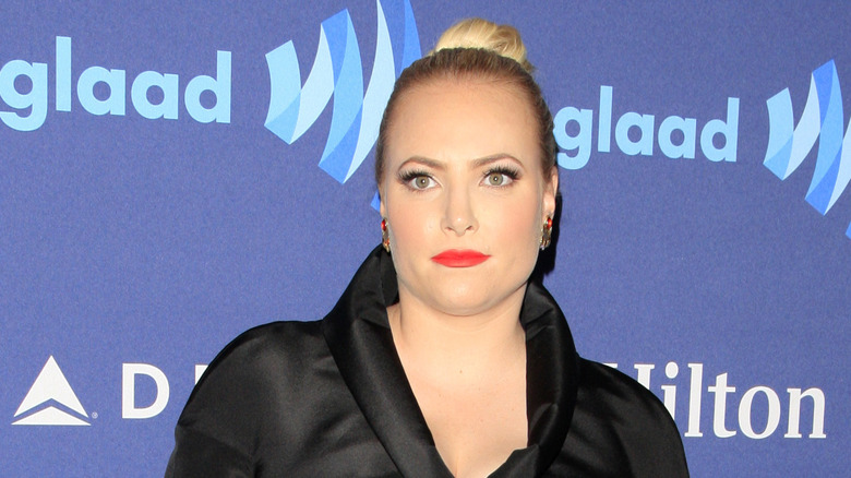 Meghan McCain poses in a black pantsuit with her hair in a bun.