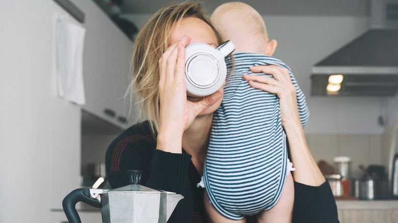 woman drinking coffee holding baby