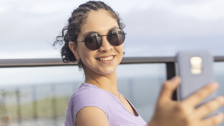 woman smiling taking beach selfie