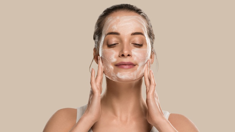 Woman with cleanser on face smiling