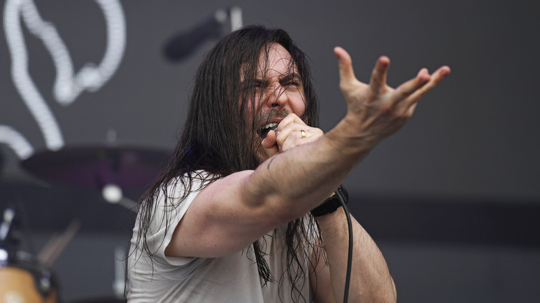 Andrew W.K. performing singing into microphone with hand outstretched