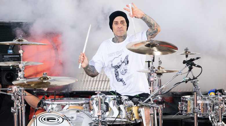 Travis Barker drumming on smoke-filled stage