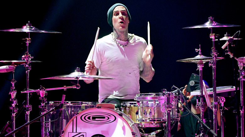 Travis Barker drumming onstage in white