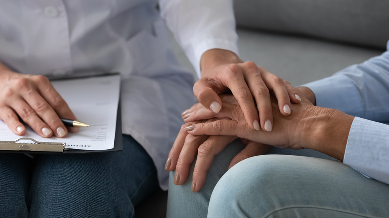 social worker and client touching hands