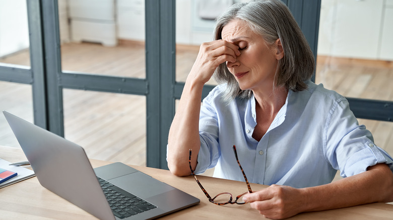 Older woman holding head at computer