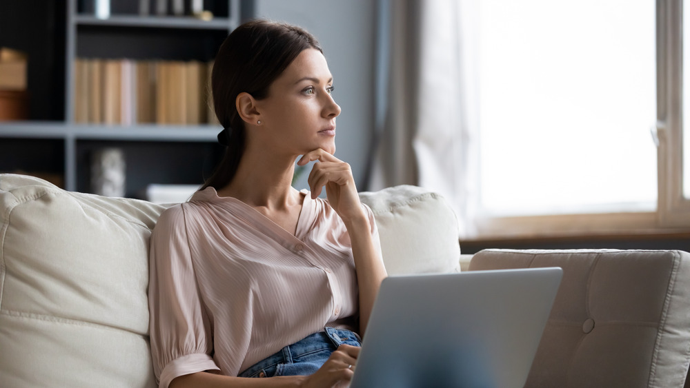 Woman daydreaming while on laptop 