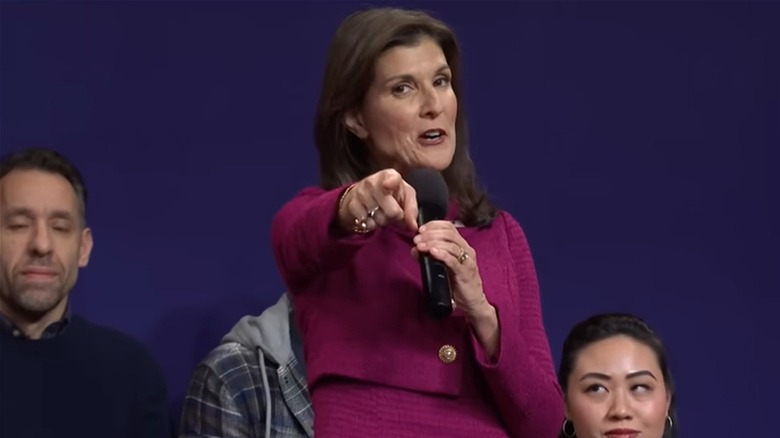 Nikki Haley holding microphone, pointing to camera on Saturday Night Live