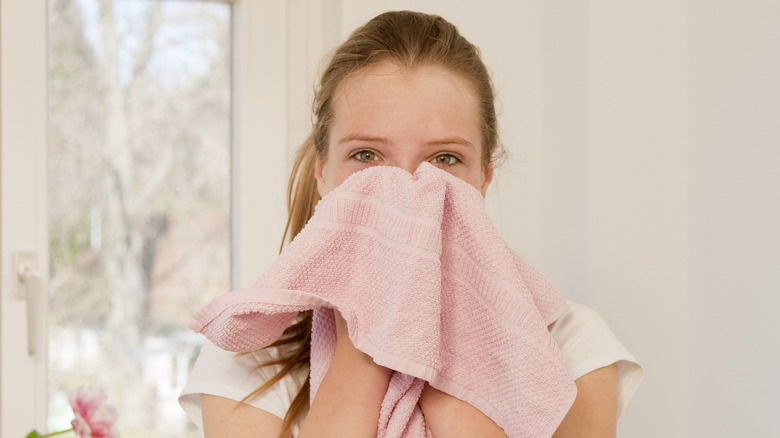 woman washing face with pink towel