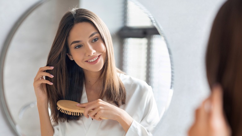 Lady brushing her hair in front of mirror