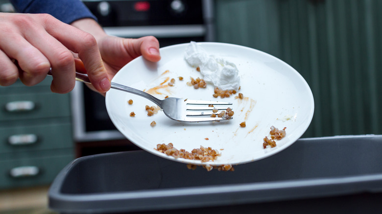 scraping plate into trash can