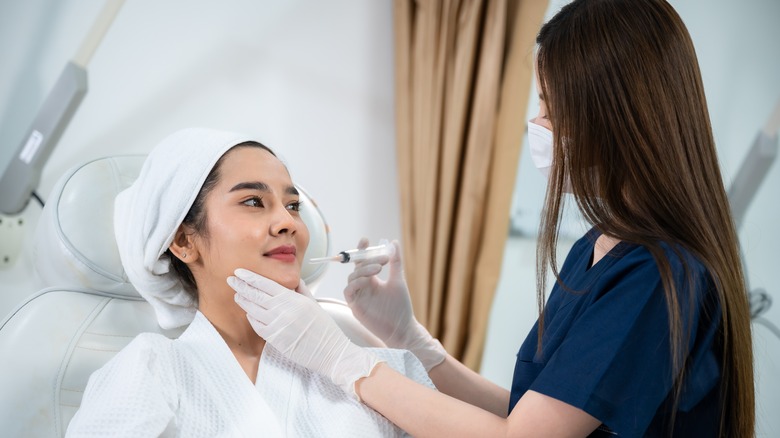 Nurse delivering injection to face