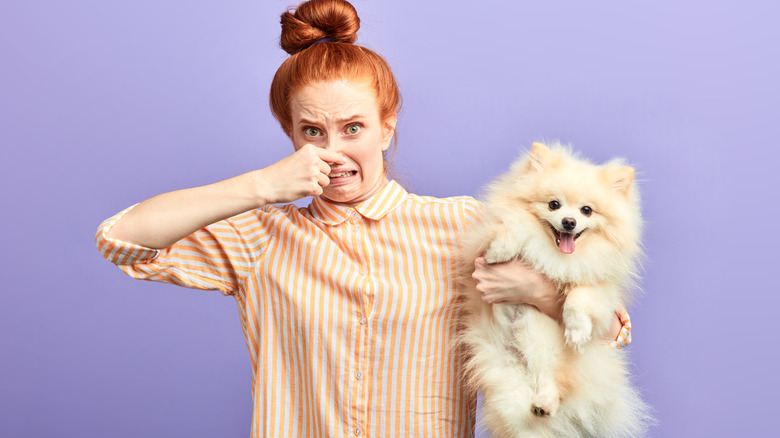 woman holding dog and pinching her nose