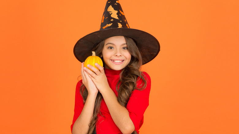 Teen girl in witch's hat with pumpkin