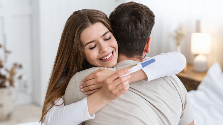 Couple hugging holding pregnancy test